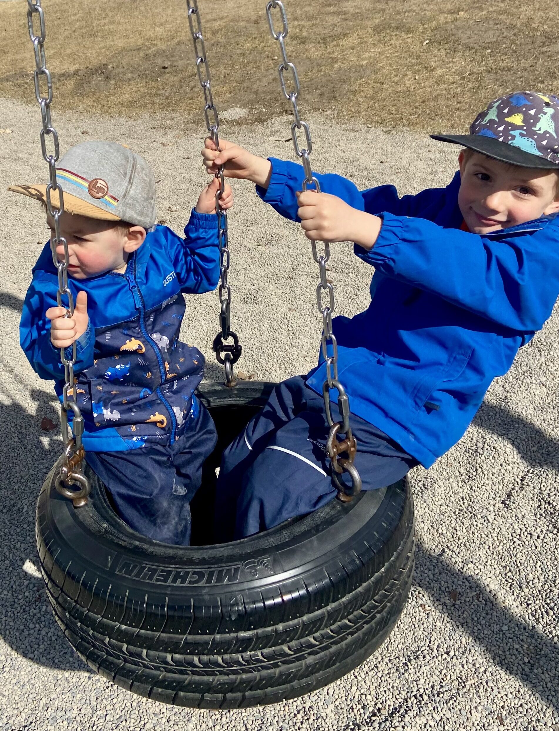 Two toddler boys on a tire swing
