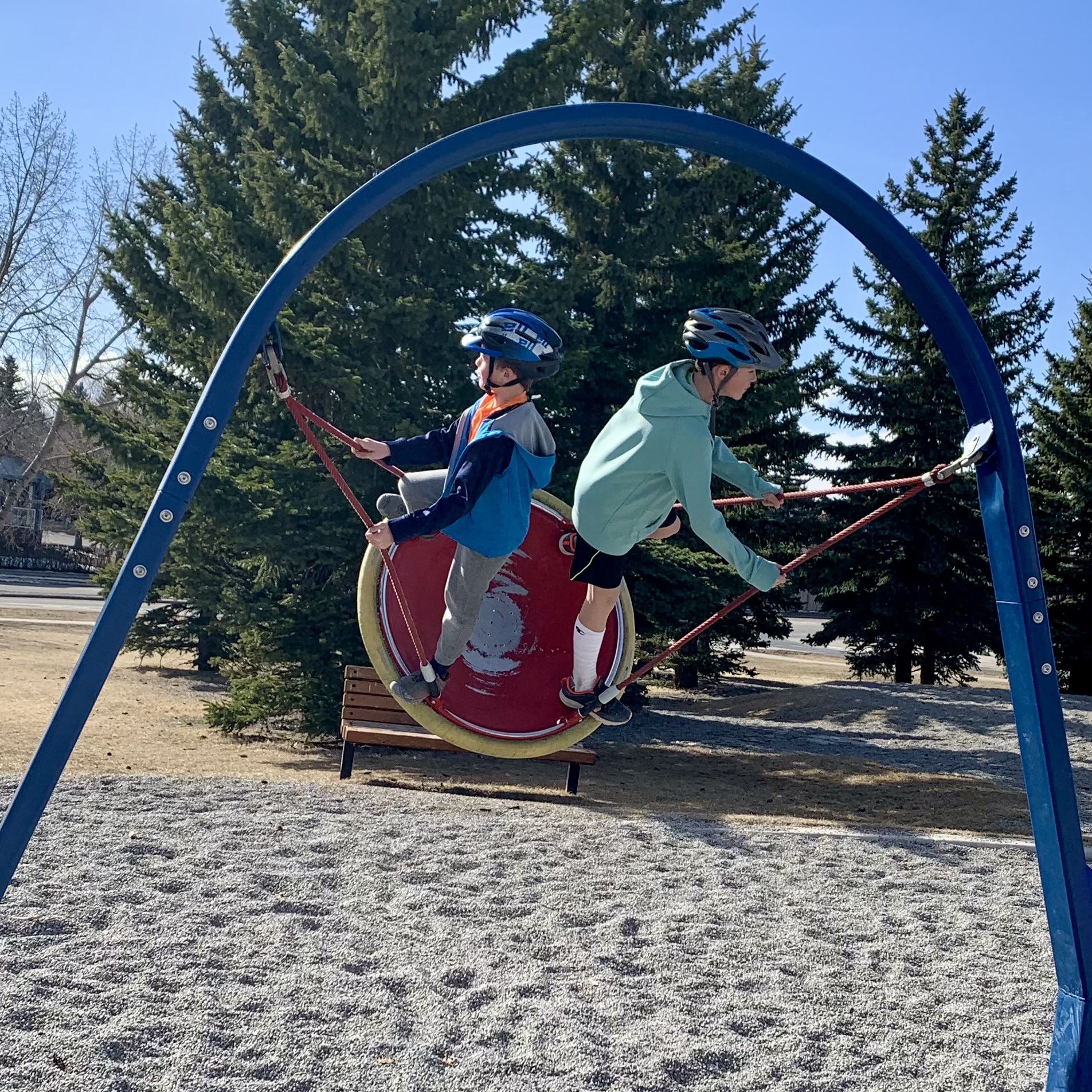 Two boys swinging on a saucer swing