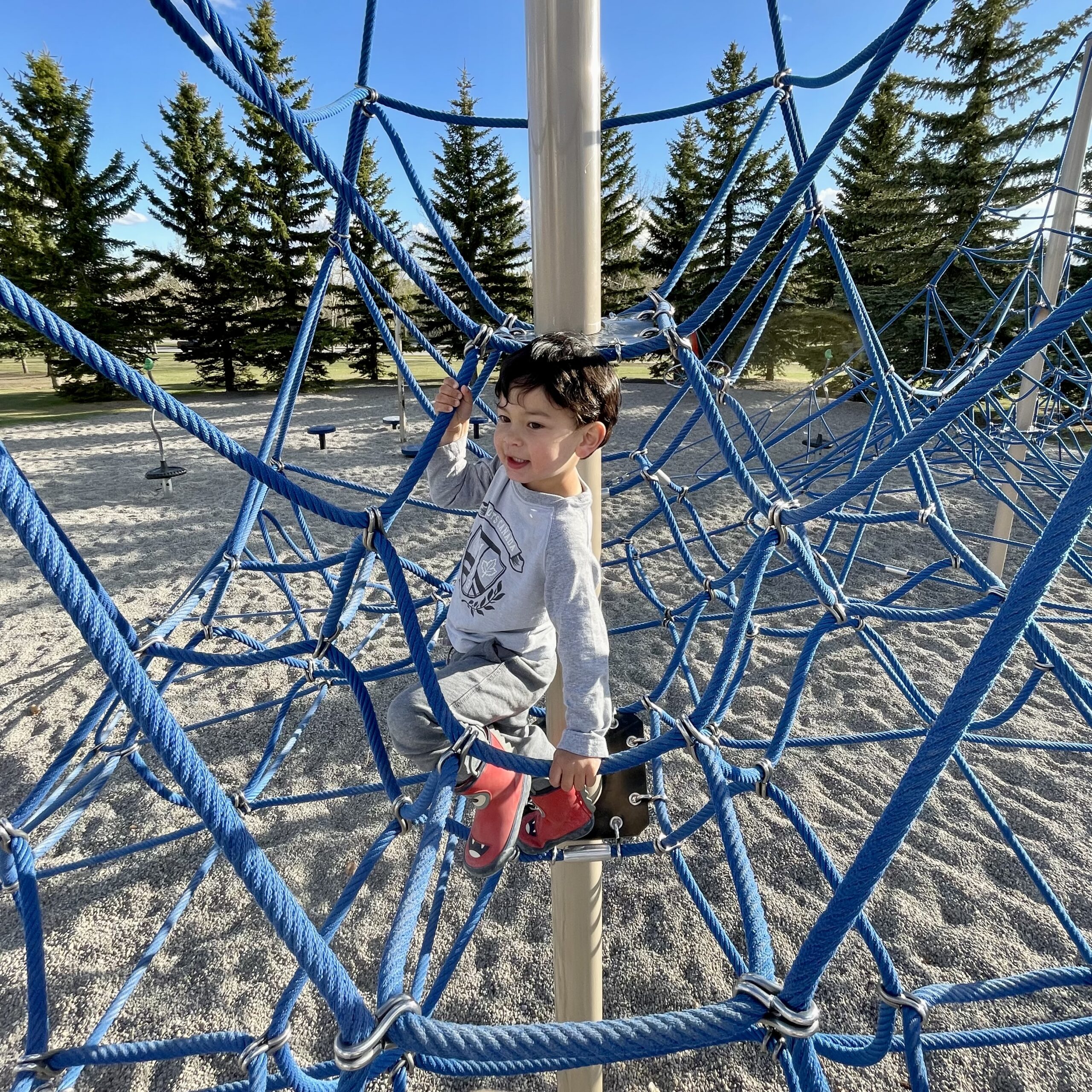 Toddler boy climbing on net structure
