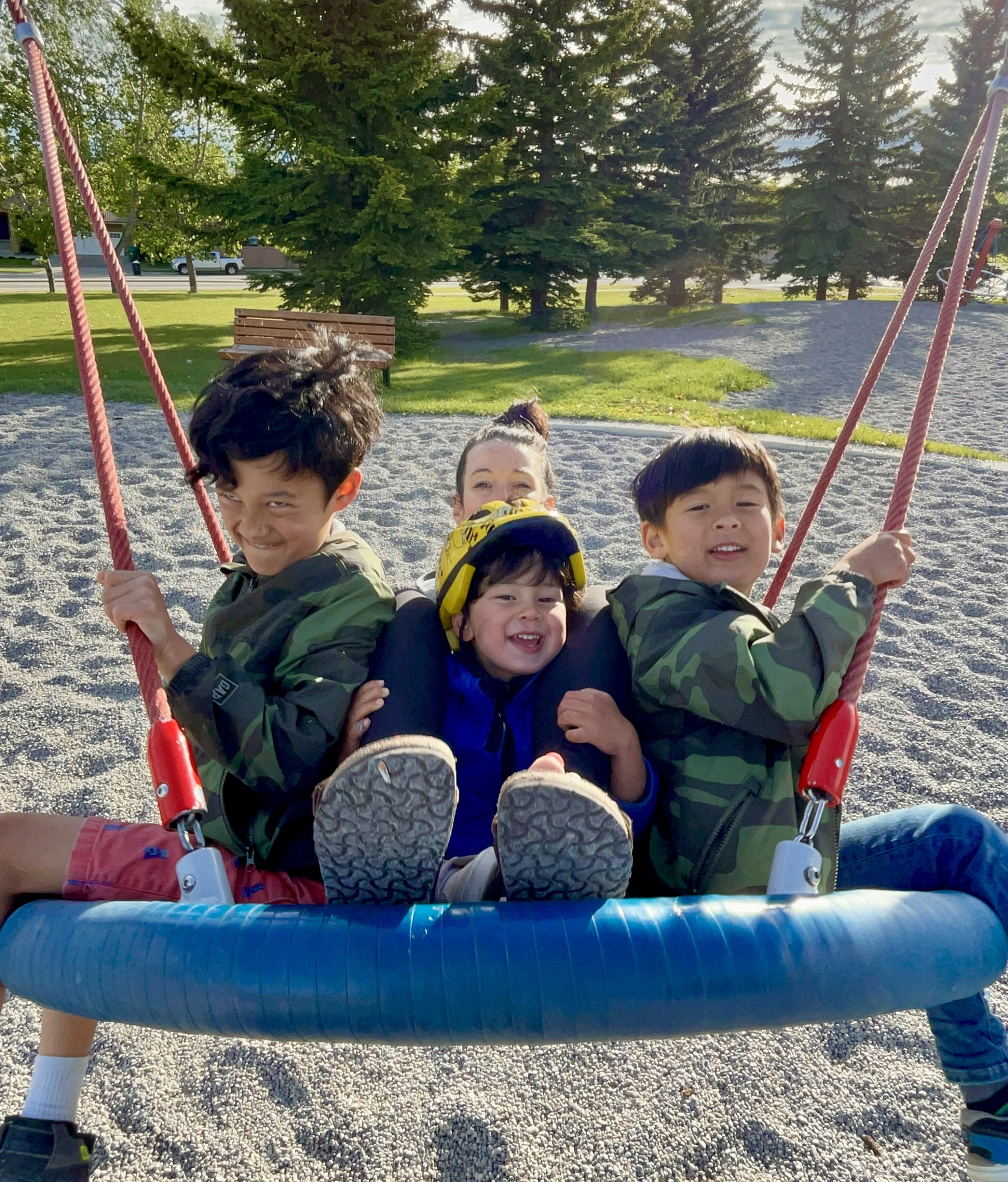 Mom and three sons swinging on the saucer swing